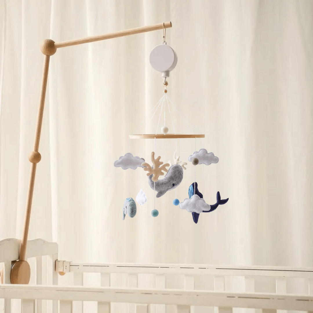 Mobile musical pour bébé fait en bois, en laine et en feutre avec des motifs de baleines, des nuages et des coraux