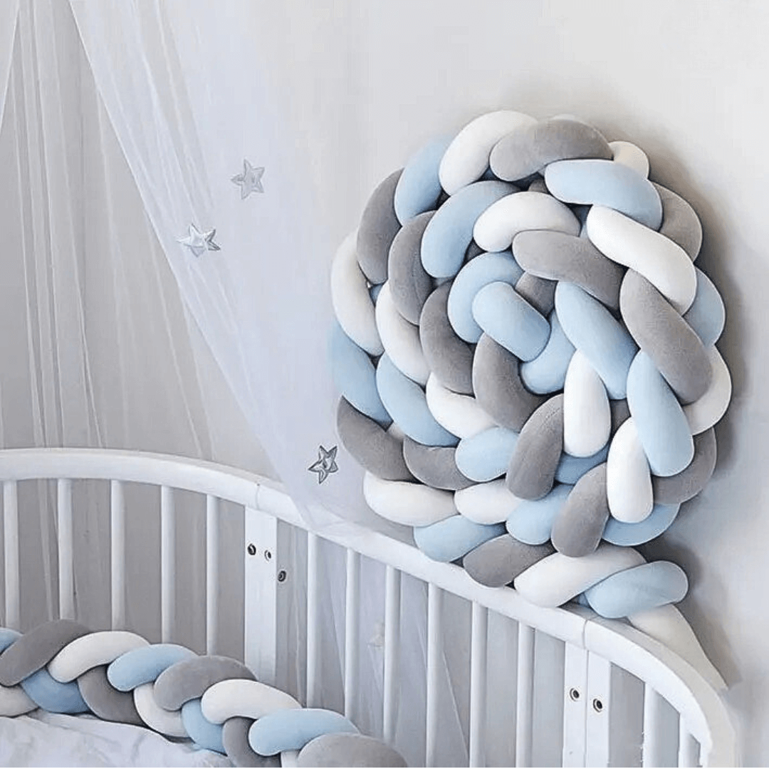 Tresse de lit bleu gris blanc installée dans un lit bébé
